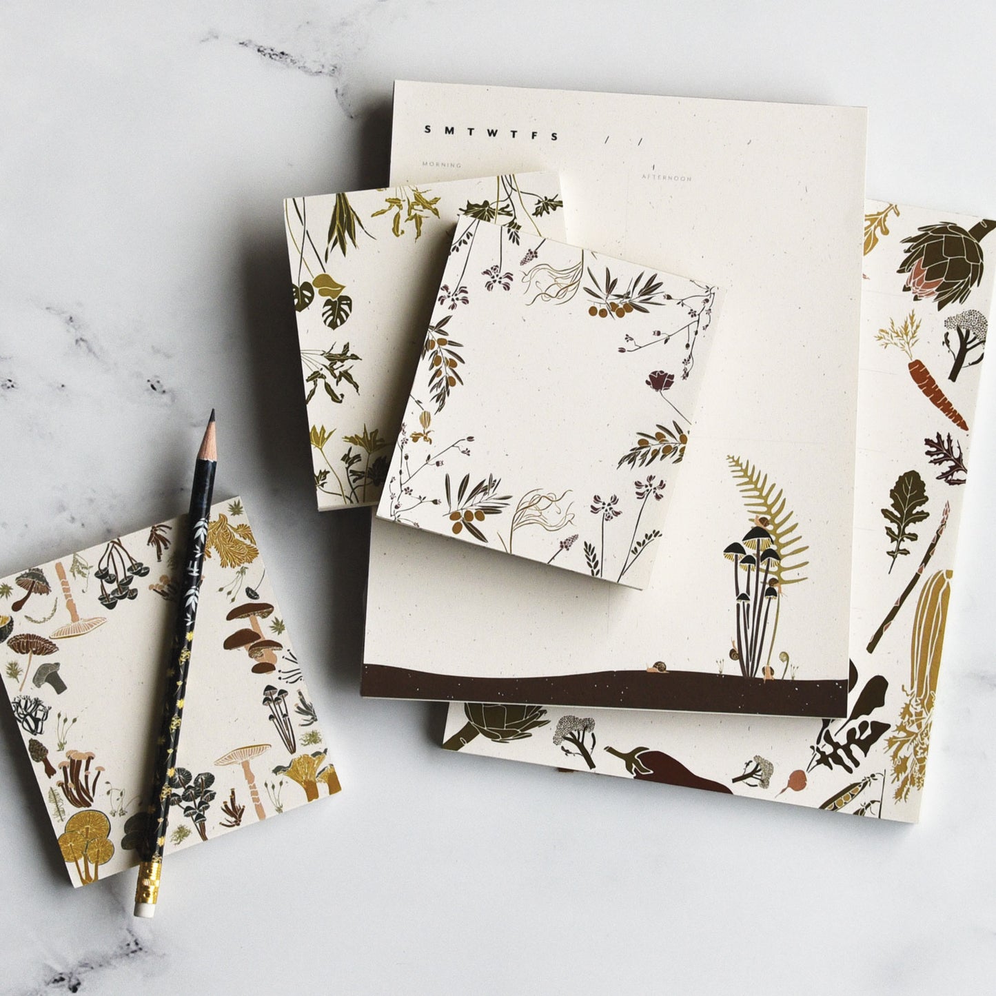 Sustainable packaging the Olive Grove Mini notepad is on display in the center among various nature inspired designs, designed by katie forte of june & december